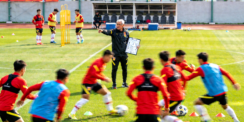 国家队在训练基地进行高强度备战训练，主教练在场边指导球员