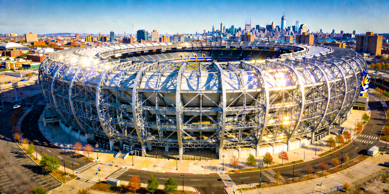 纽约大都会人寿体育场外部全景，巨大的椭圆形钢结构在阳光下熠熠生辉