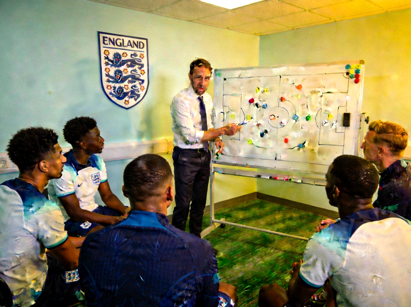 英格兰队主教练索斯盖特在战术板前向贝林厄姆、萨卡等球员讲解